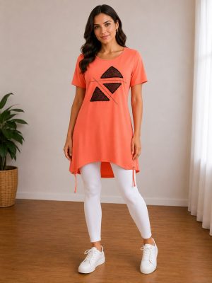 Ženska nosi elegantno oranžno tuniko s potiskom in belimi pajkicami.